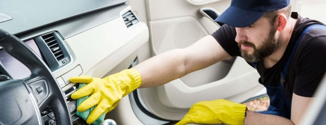 A man is cleaning the interiors of a car