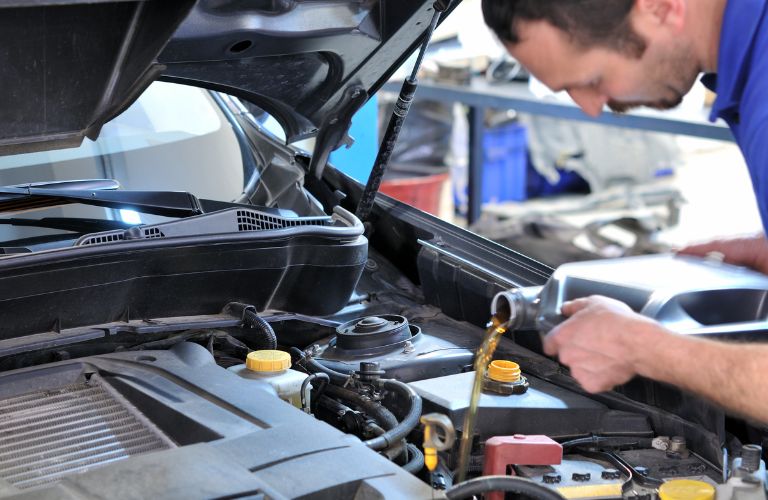 A man pouring oil in a car.